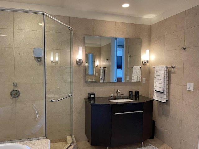 bathroom with an enclosed shower, vanity, radiator, and tile walls