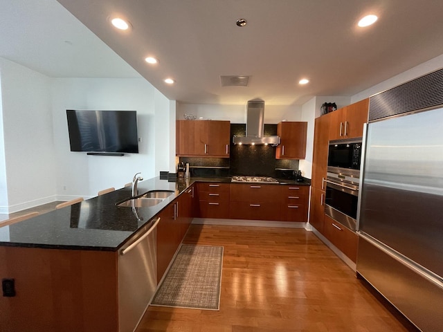 kitchen featuring sink, light hardwood / wood-style flooring, appliances with stainless steel finishes, kitchen peninsula, and island exhaust hood