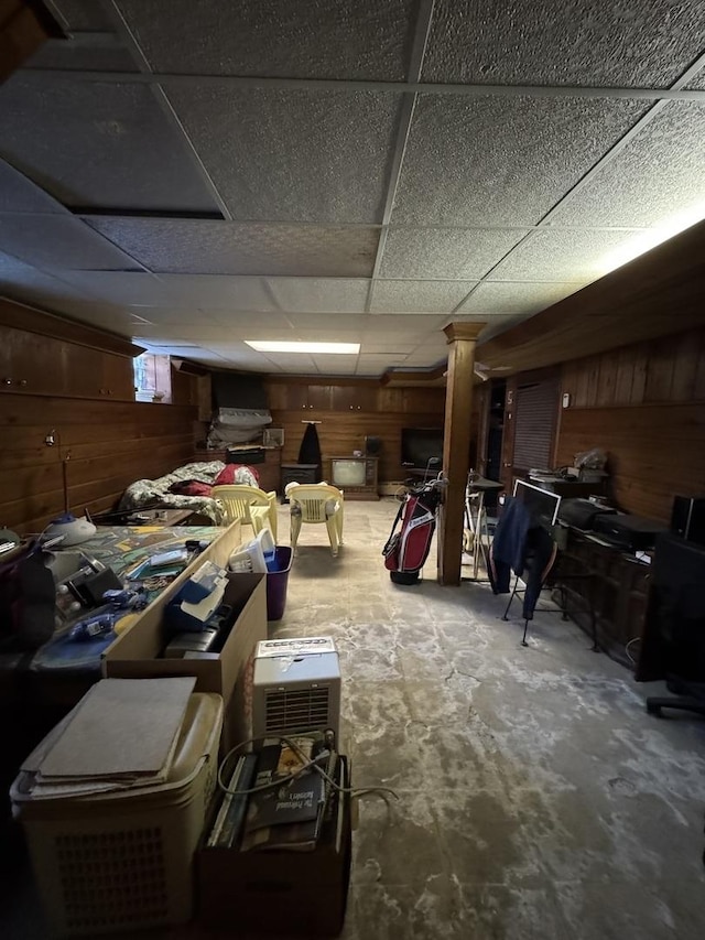 below grade area with wood walls and a drop ceiling