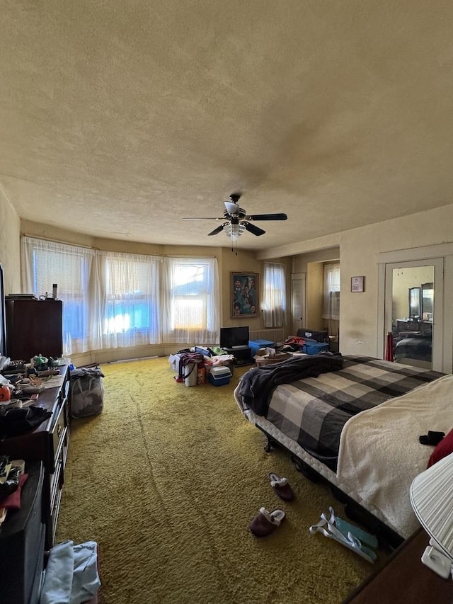 carpeted bedroom featuring a ceiling fan and a textured ceiling