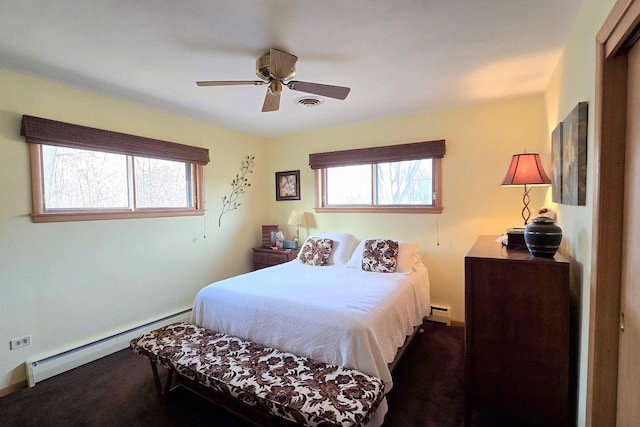 bedroom with multiple windows, dark colored carpet, ceiling fan, and baseboard heating