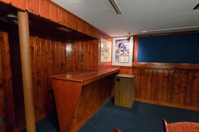 bar featuring dark colored carpet and wood walls