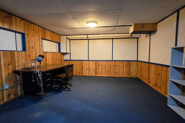 office area with wooden walls and dark colored carpet