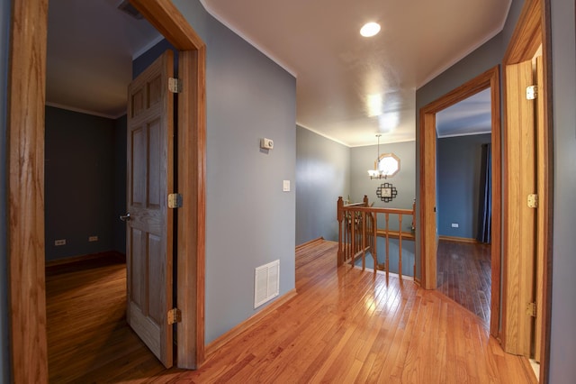 hall featuring crown molding, hardwood / wood-style floors, and a chandelier