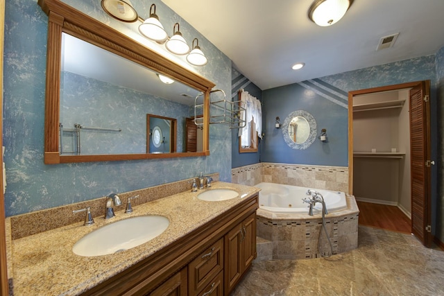 bathroom featuring vanity and tiled tub