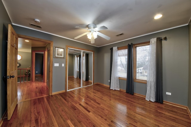 unfurnished bedroom with a closet, ornamental molding, dark hardwood / wood-style floors, and ceiling fan