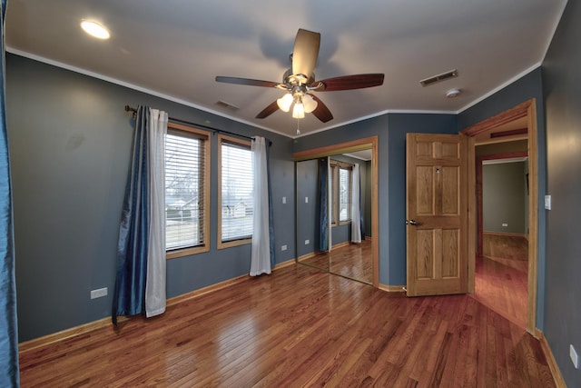 unfurnished bedroom with crown molding, ceiling fan, wood-type flooring, and a closet