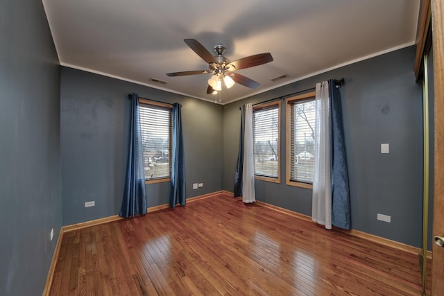 empty room featuring hardwood / wood-style floors, ornamental molding, and ceiling fan