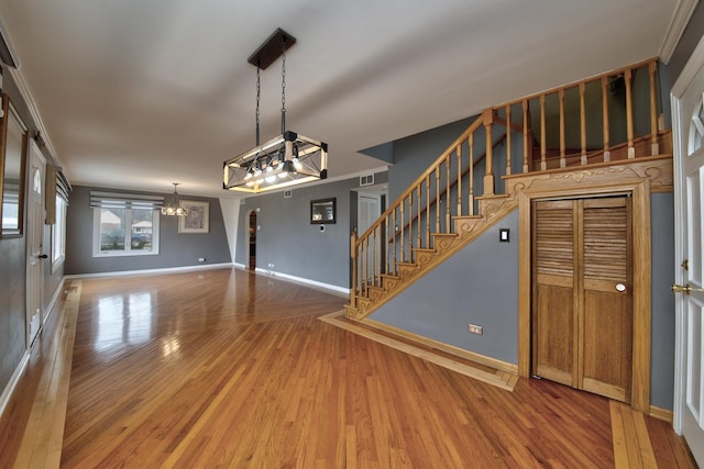 interior space featuring hardwood / wood-style flooring, crown molding, and a chandelier