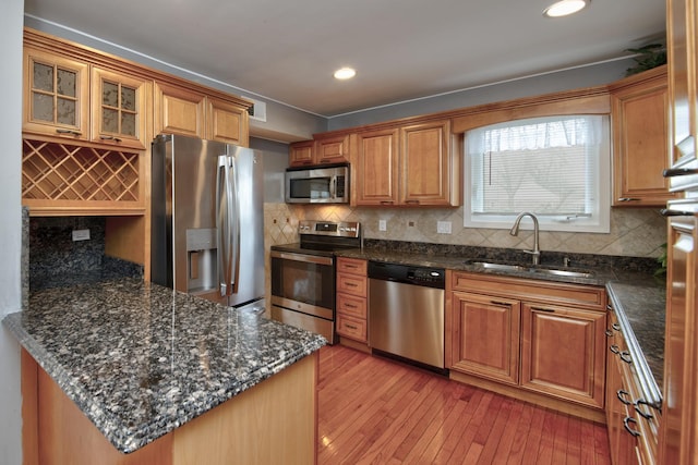 kitchen featuring decorative backsplash, appliances with stainless steel finishes, sink, and light hardwood / wood-style flooring