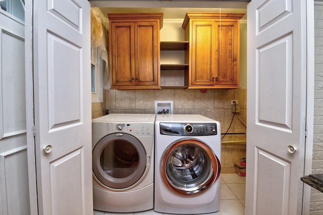 clothes washing area featuring cabinets, light tile patterned floors, and independent washer and dryer