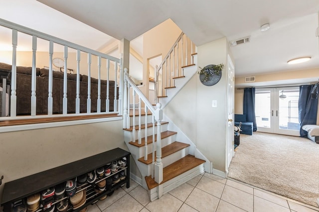 staircase with carpet floors, tile patterned floors, visible vents, and french doors