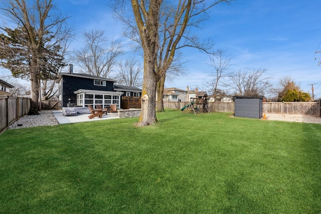 view of yard featuring a patio, a playground, a fenced backyard, and a sunroom