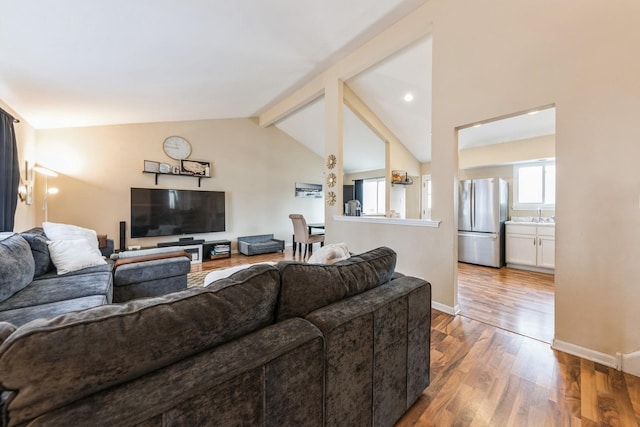 living area with vaulted ceiling with beams, baseboards, and wood finished floors