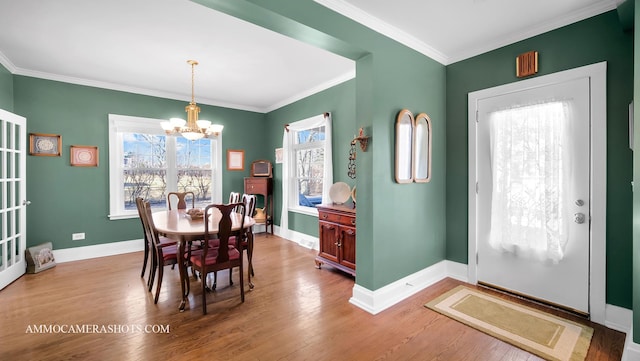 dining area with an inviting chandelier, hardwood / wood-style floors, and crown molding