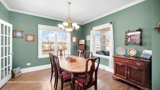 dining room featuring ornamental molding, a healthy amount of sunlight, an inviting chandelier, and light hardwood / wood-style flooring