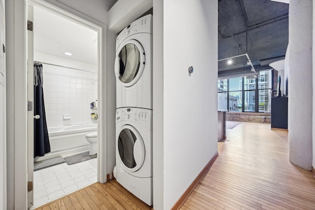 laundry room featuring light hardwood / wood-style floors and stacked washer / dryer