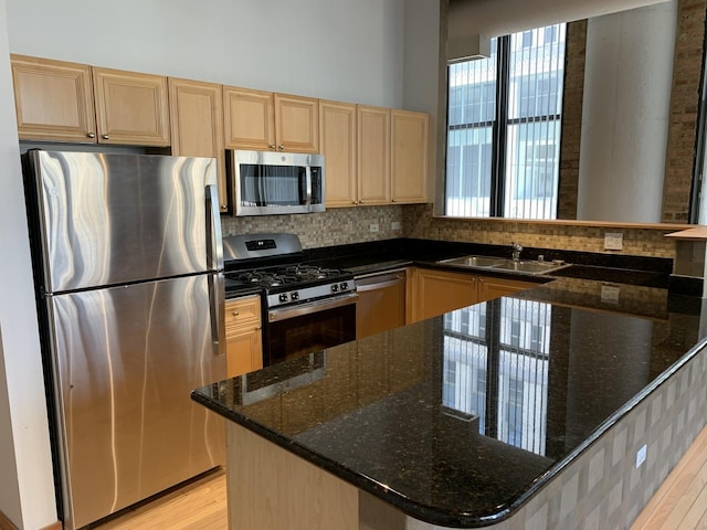 kitchen featuring stainless steel appliances, sink, a wealth of natural light, and dark stone counters