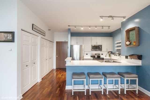 kitchen with kitchen peninsula, a breakfast bar, sink, appliances with stainless steel finishes, and white cabinets