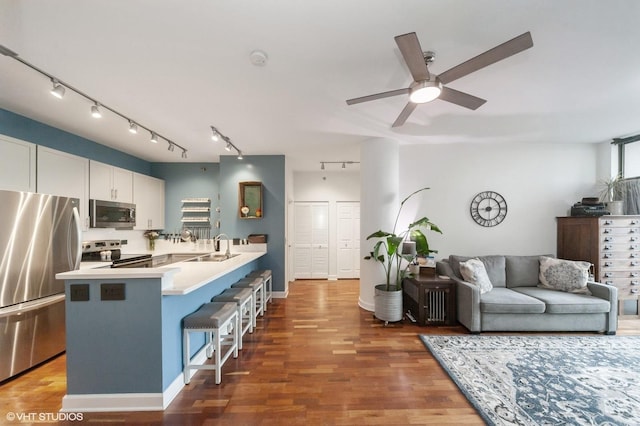 kitchen with a breakfast bar area, stainless steel appliances, sink, white cabinetry, and kitchen peninsula