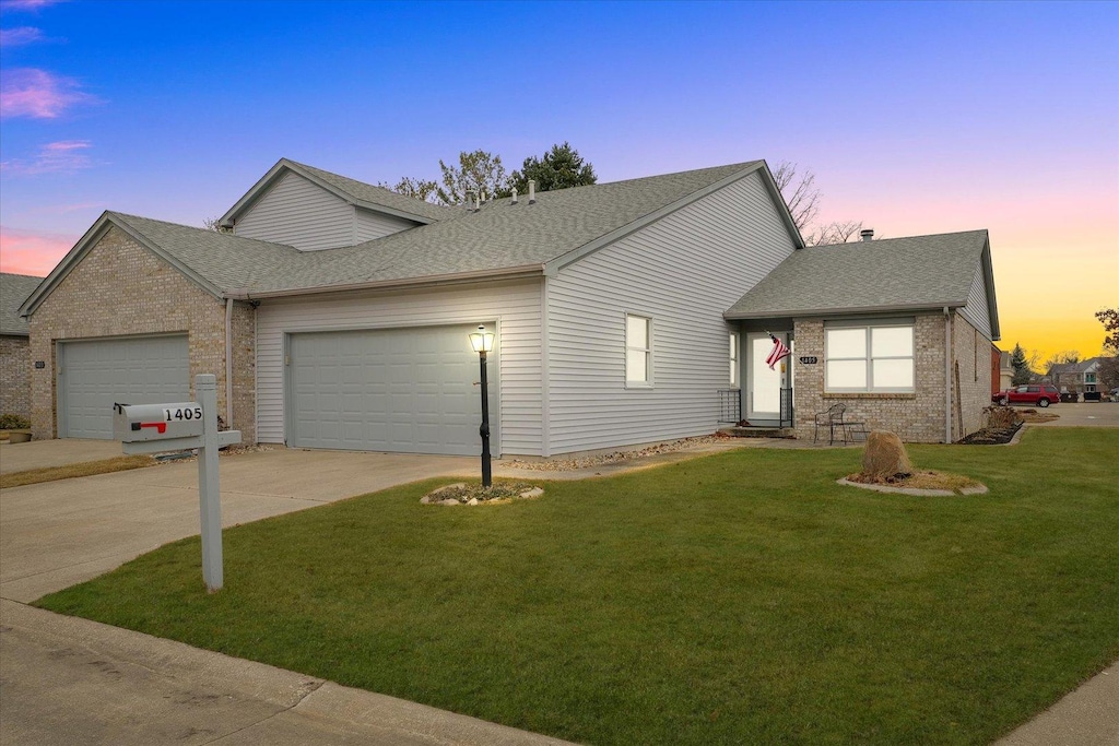 ranch-style house featuring a garage and a lawn