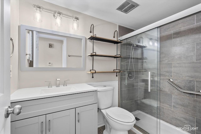 bathroom with vanity, a shower with shower door, and toilet