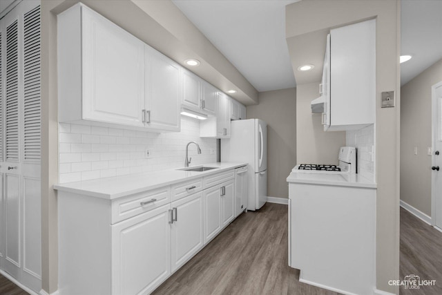 kitchen with sink, white cabinets, white appliances, and light wood-type flooring