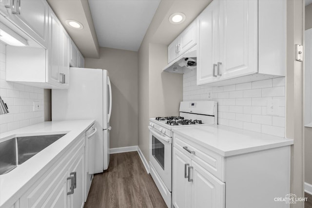 kitchen featuring sink, dark wood-type flooring, white gas range oven, white cabinets, and decorative backsplash