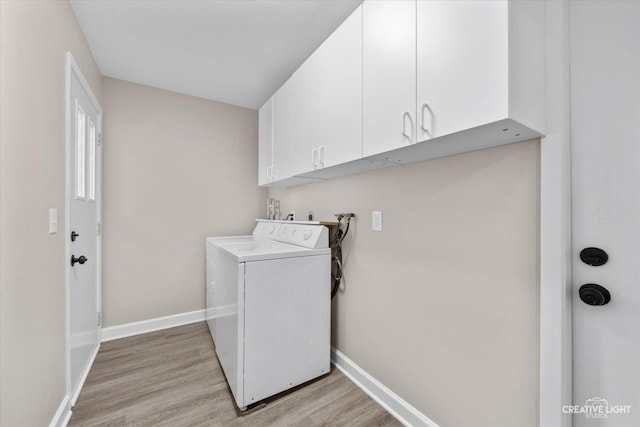 clothes washing area with cabinets, washer and clothes dryer, and light wood-type flooring