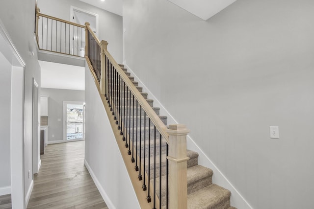 stairway with wood-type flooring and a high ceiling