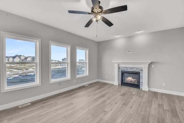 unfurnished living room with ceiling fan, a fireplace, and light wood-type flooring