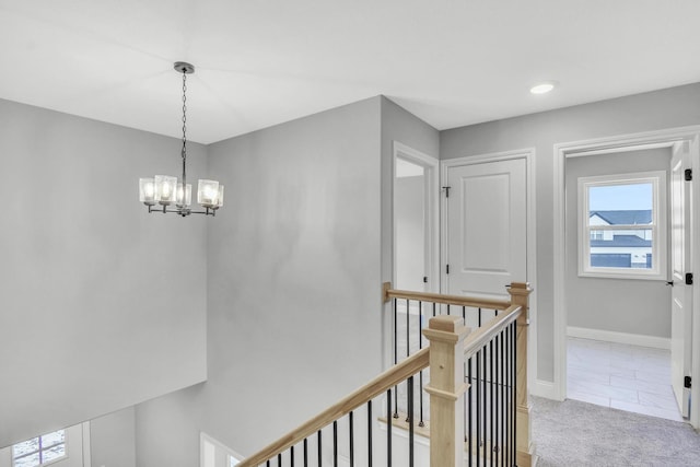 hall featuring light colored carpet and a notable chandelier