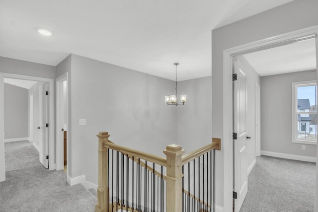 hallway with light carpet and a notable chandelier