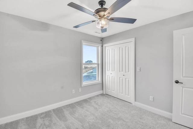 unfurnished bedroom with light carpet, a closet, and ceiling fan