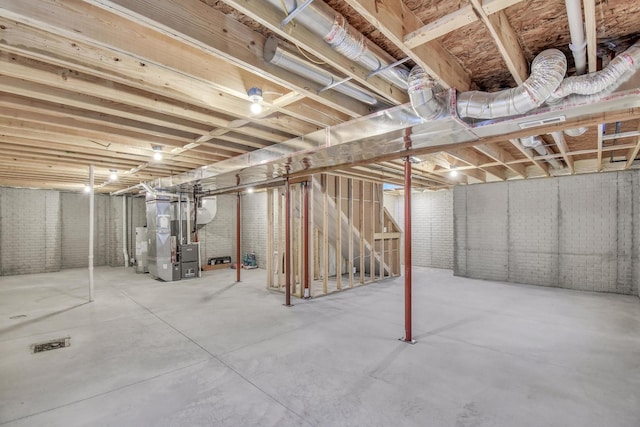 basement featuring brick wall and heating unit