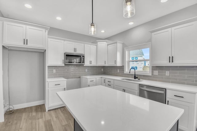 kitchen with stainless steel appliances, white cabinetry, sink, and pendant lighting