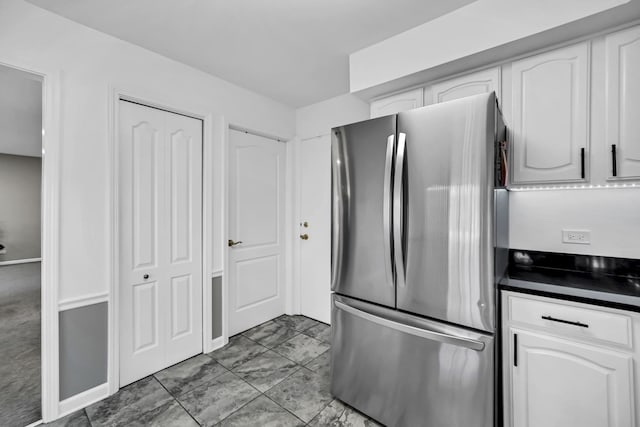 kitchen featuring white cabinetry, dark countertops, and freestanding refrigerator