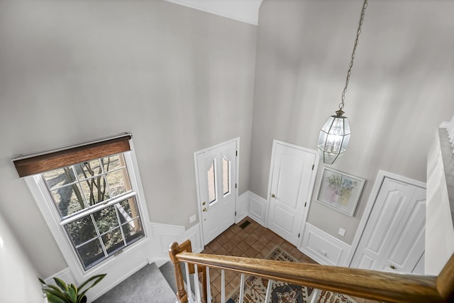 entrance foyer with a wainscoted wall, a high ceiling, a decorative wall, and a notable chandelier