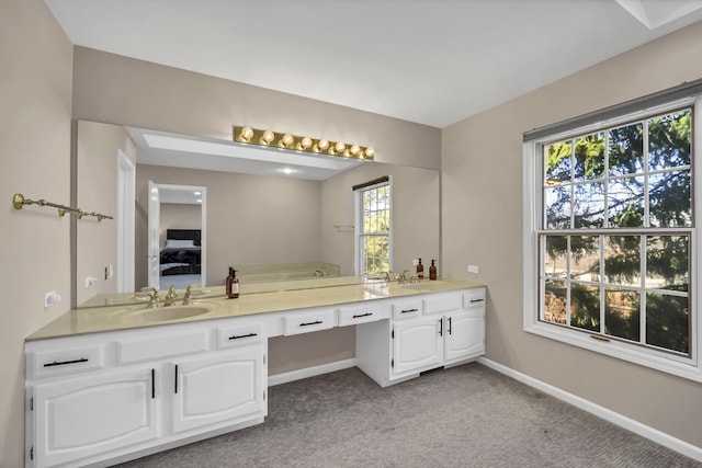 ensuite bathroom with double vanity, ensuite bathroom, baseboards, and a sink