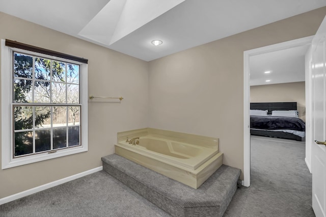 ensuite bathroom featuring connected bathroom, baseboards, and a bath