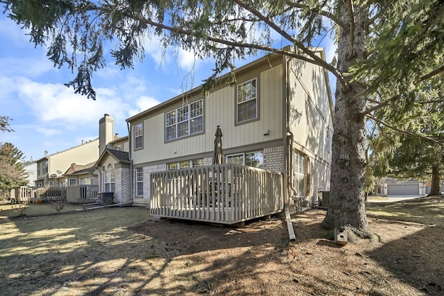 back of house featuring a wooden deck, brick siding, central AC, and a chimney