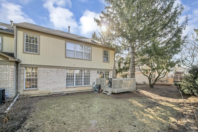 rear view of property featuring brick siding and a deck