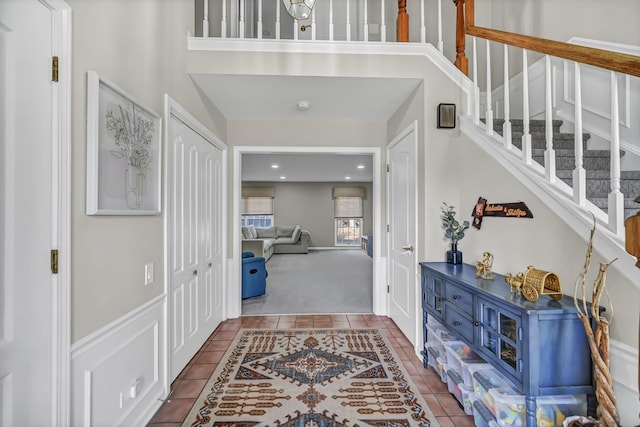 tiled entrance foyer featuring stairway, recessed lighting, a towering ceiling, and carpet floors