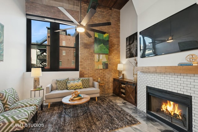 living room featuring a high ceiling, ceiling fan, brick wall, and a fireplace