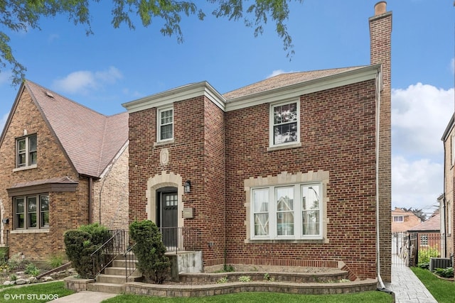 tudor-style house with cooling unit and a front lawn