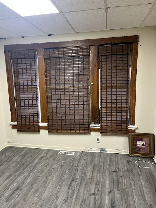 spare room featuring hardwood / wood-style flooring and a drop ceiling