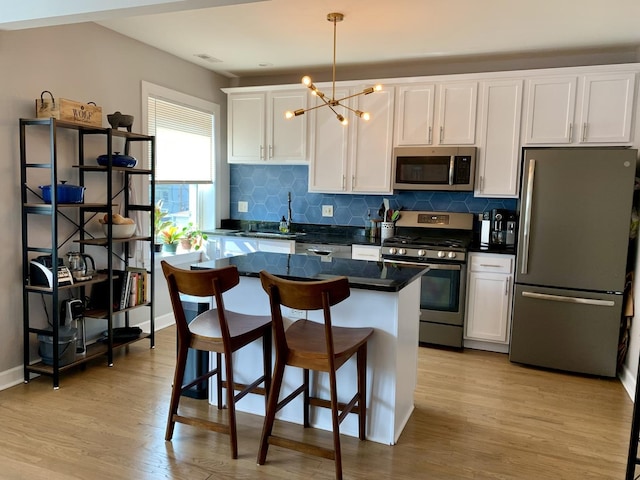 kitchen featuring white cabinetry, decorative light fixtures, light hardwood / wood-style flooring, a kitchen island, and stainless steel appliances