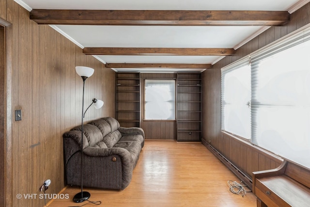 sitting room featuring crown molding, light hardwood / wood-style flooring, a baseboard radiator, beamed ceiling, and wood walls