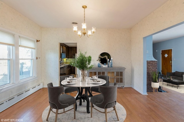 dining area featuring a baseboard radiator, a chandelier, and light hardwood / wood-style floors