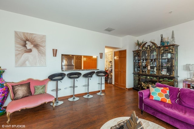 living area with baseboards, visible vents, and wood finished floors